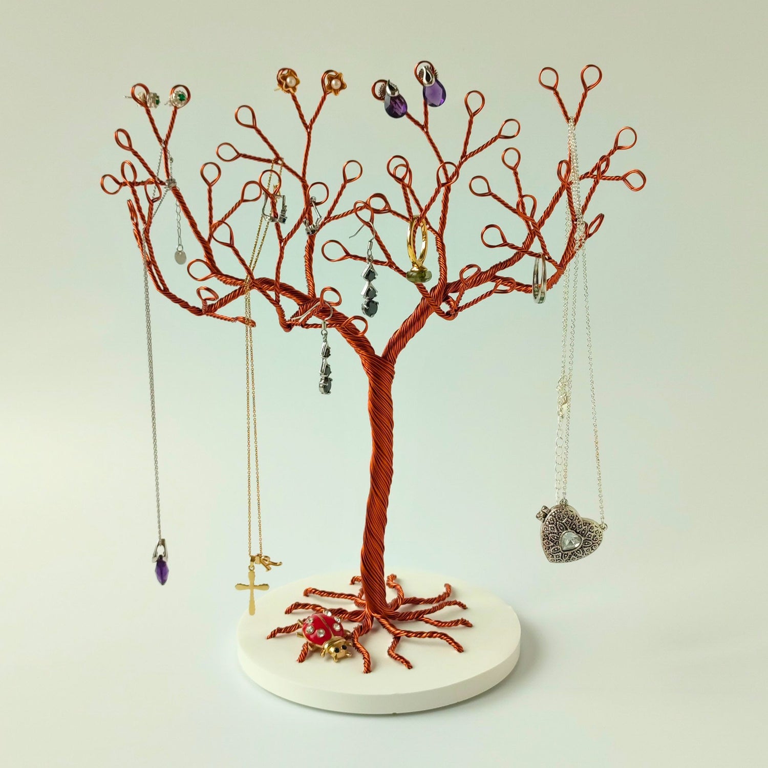 Copper jewelry tree stand with ceramic tray holding accessories