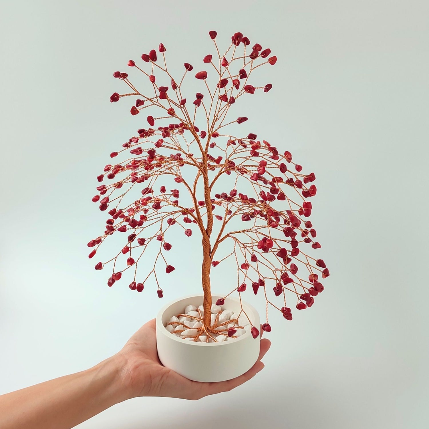 Coral gemstone copper large tree with decorative stones shown in hand to show size and proportion