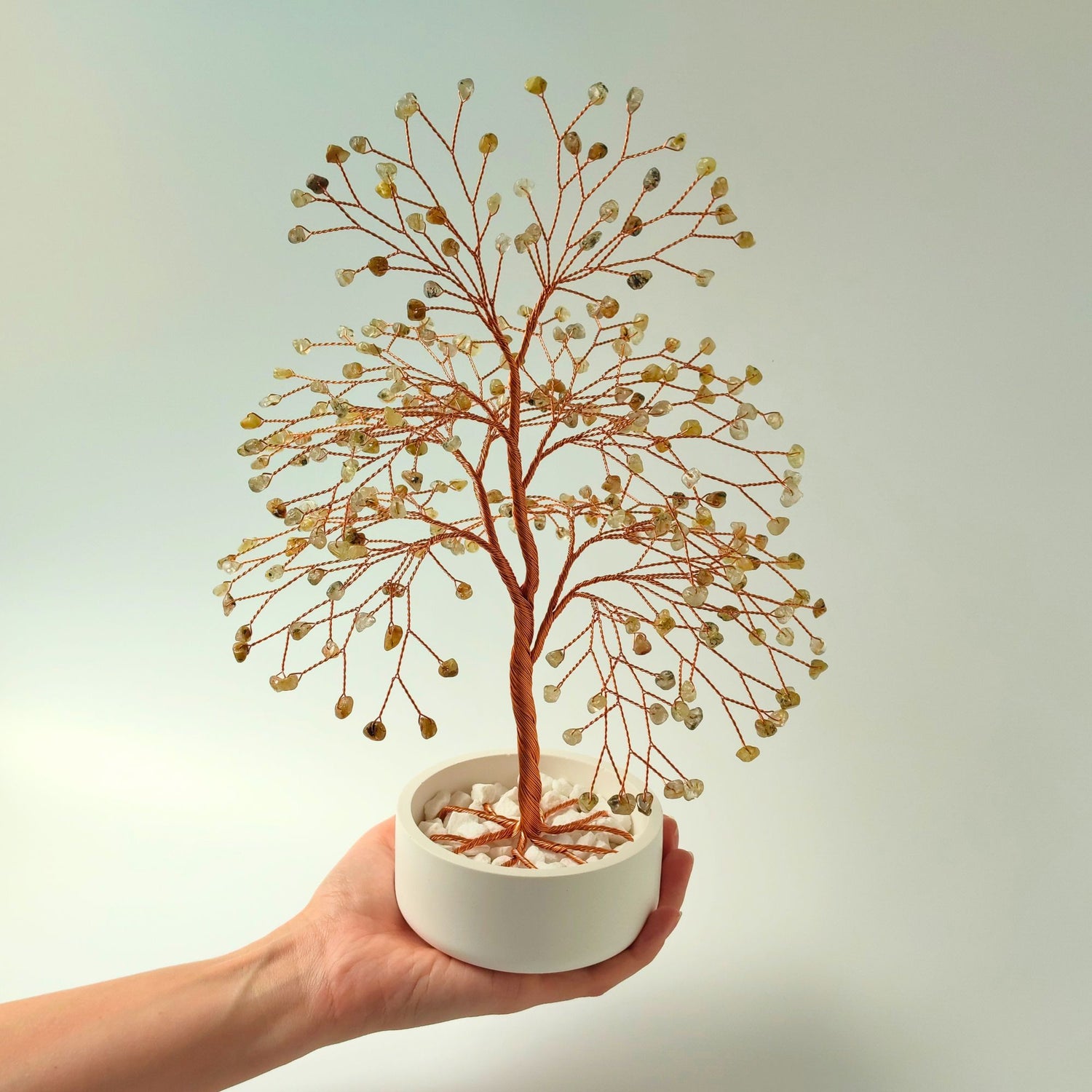 Rutilated quartz copper large tree with decorative stones shown in hand to show size and proportion