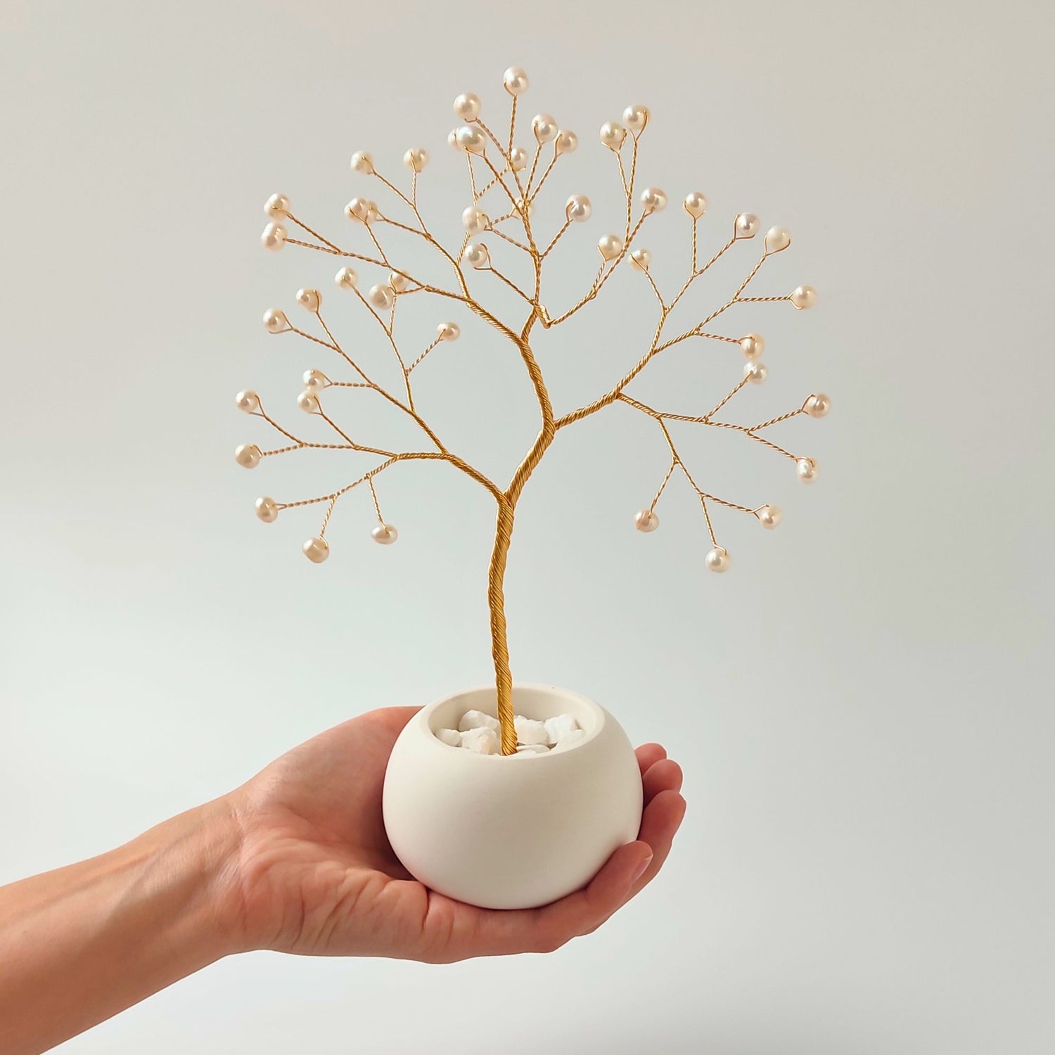 Size reference – pearl small gold tree sculpture held in hand to show scale