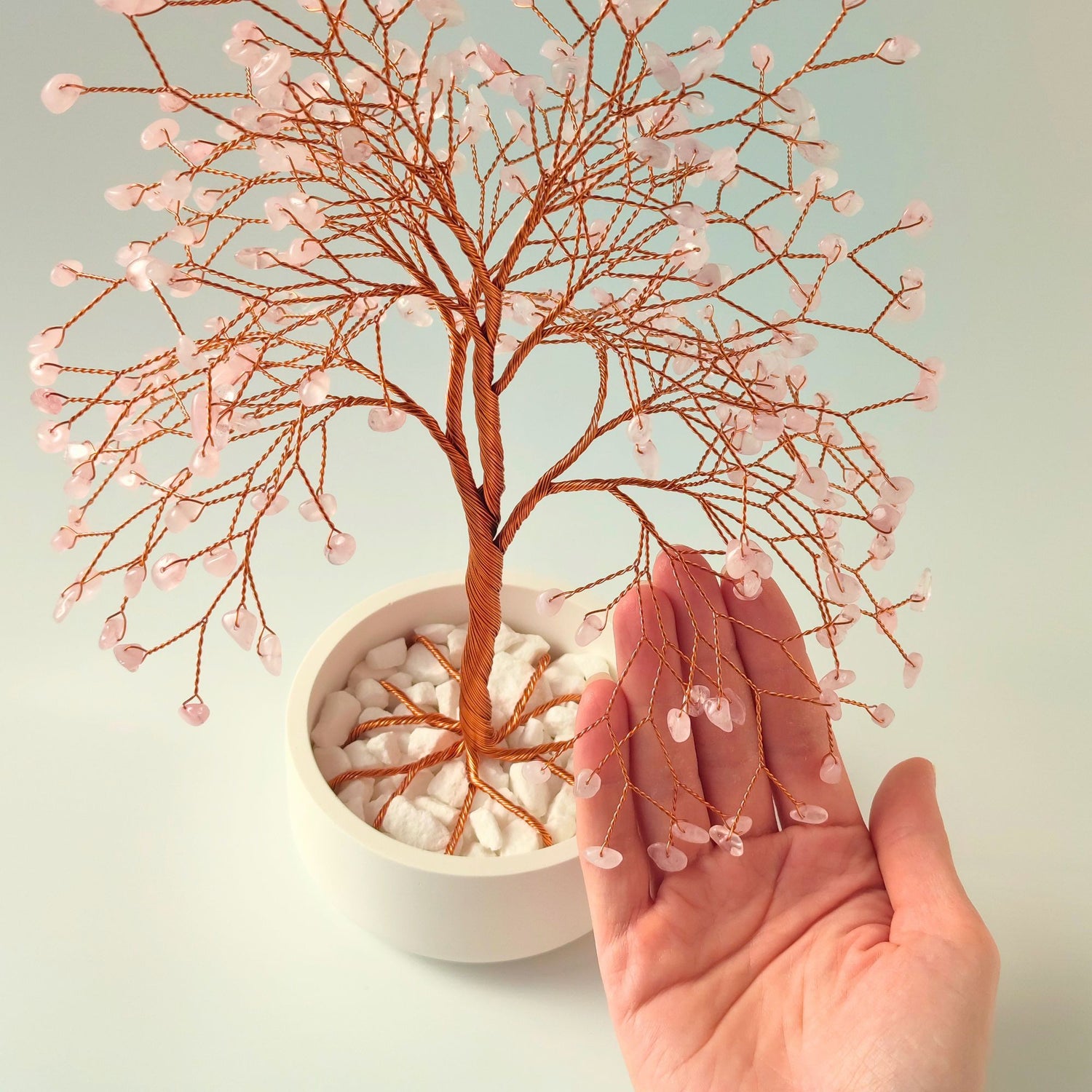 280 of rose quartz gemstones compared with hand to show size and proportion