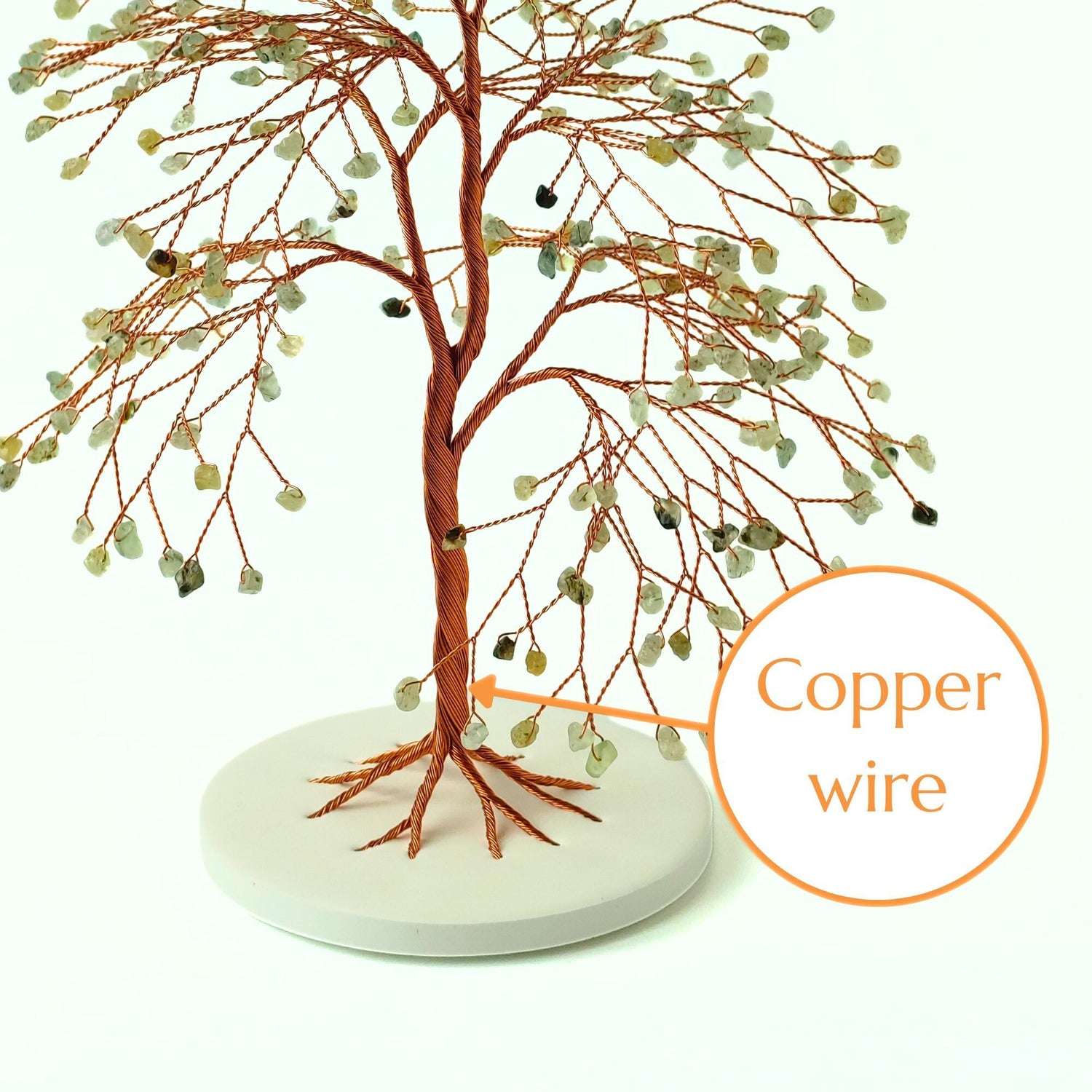 Decorative tree made of copper wire with a white base on a light green background