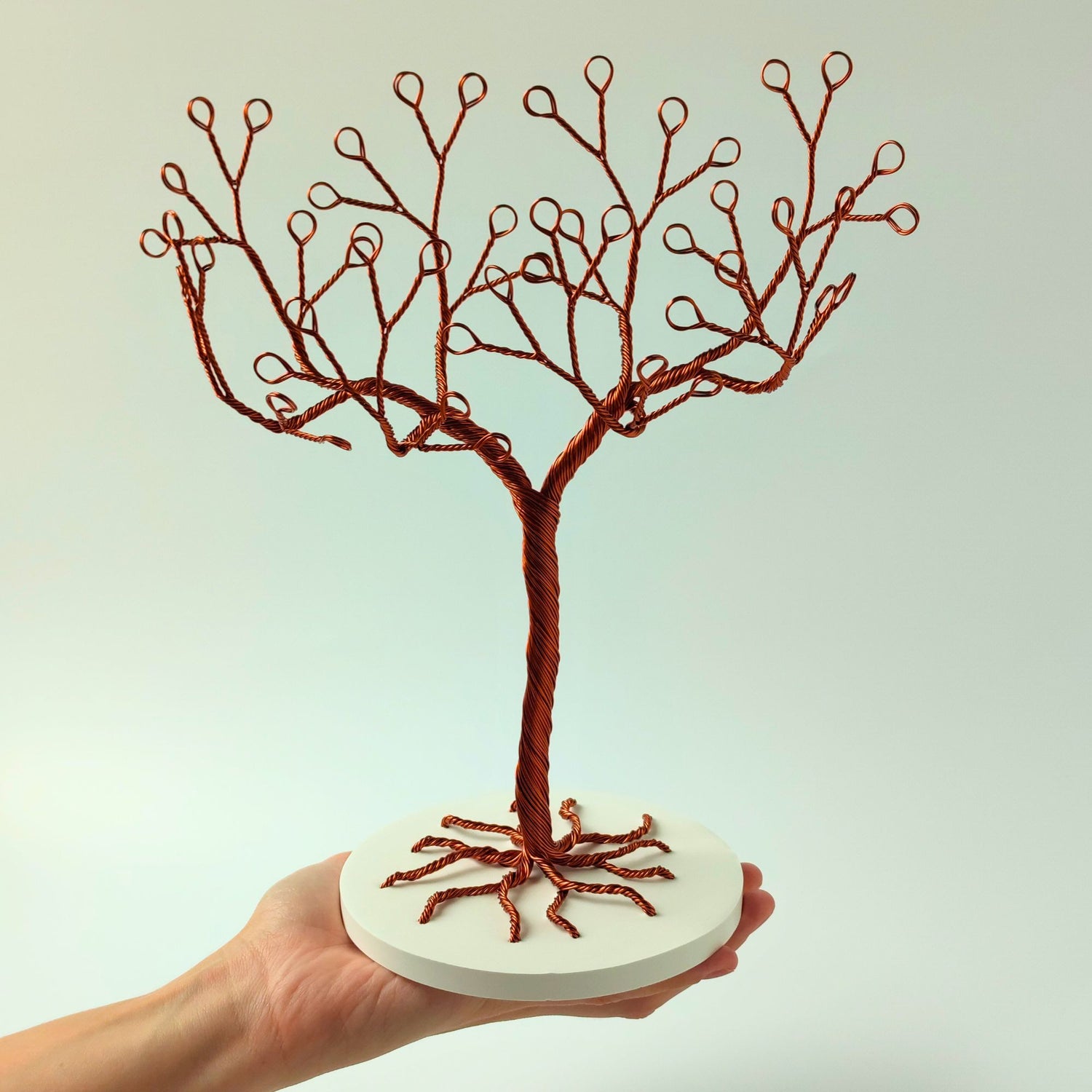Small copper wire jewelry stand with tray shown in hand for scale