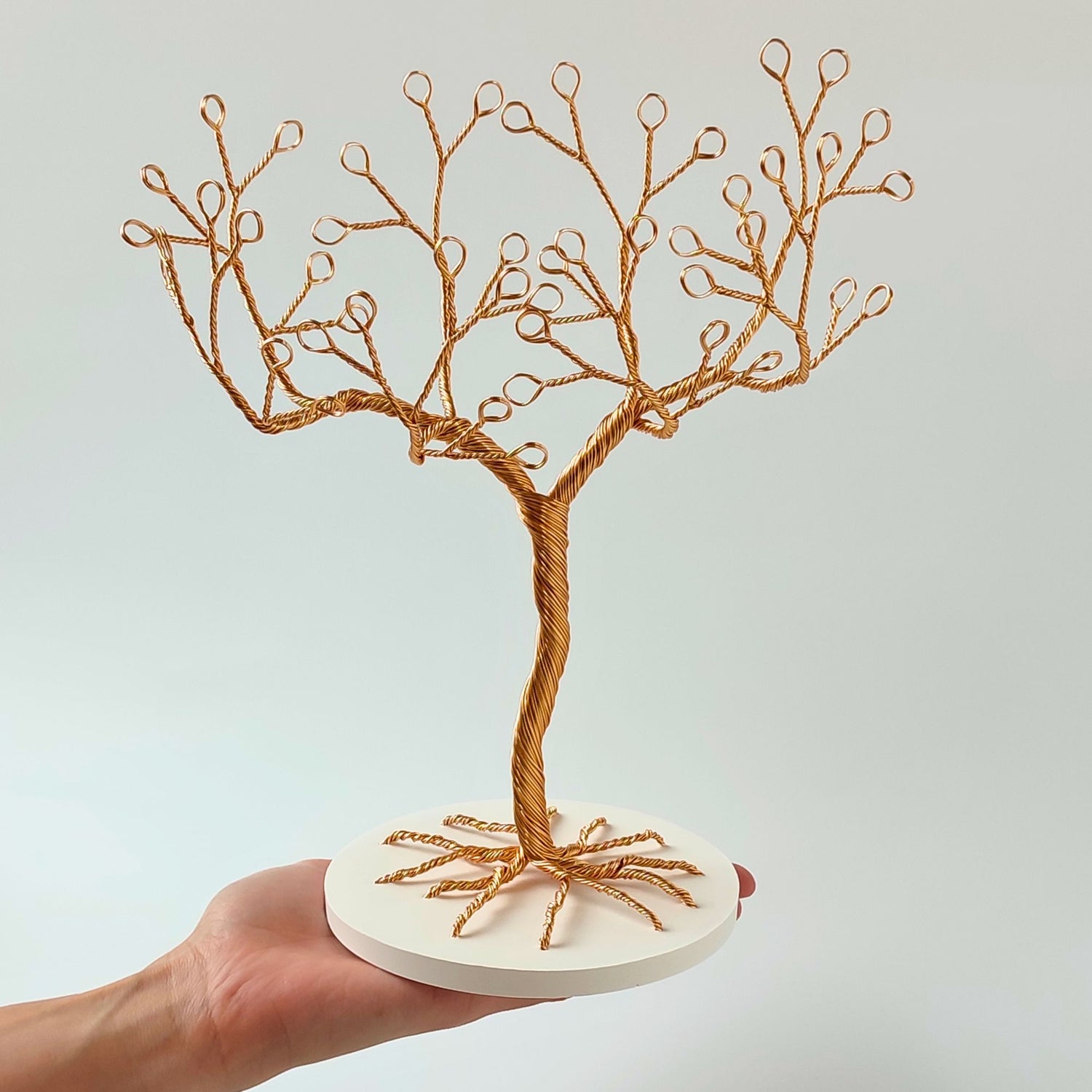 Small gilt wire jewelry stand with tray shown in hand for scale