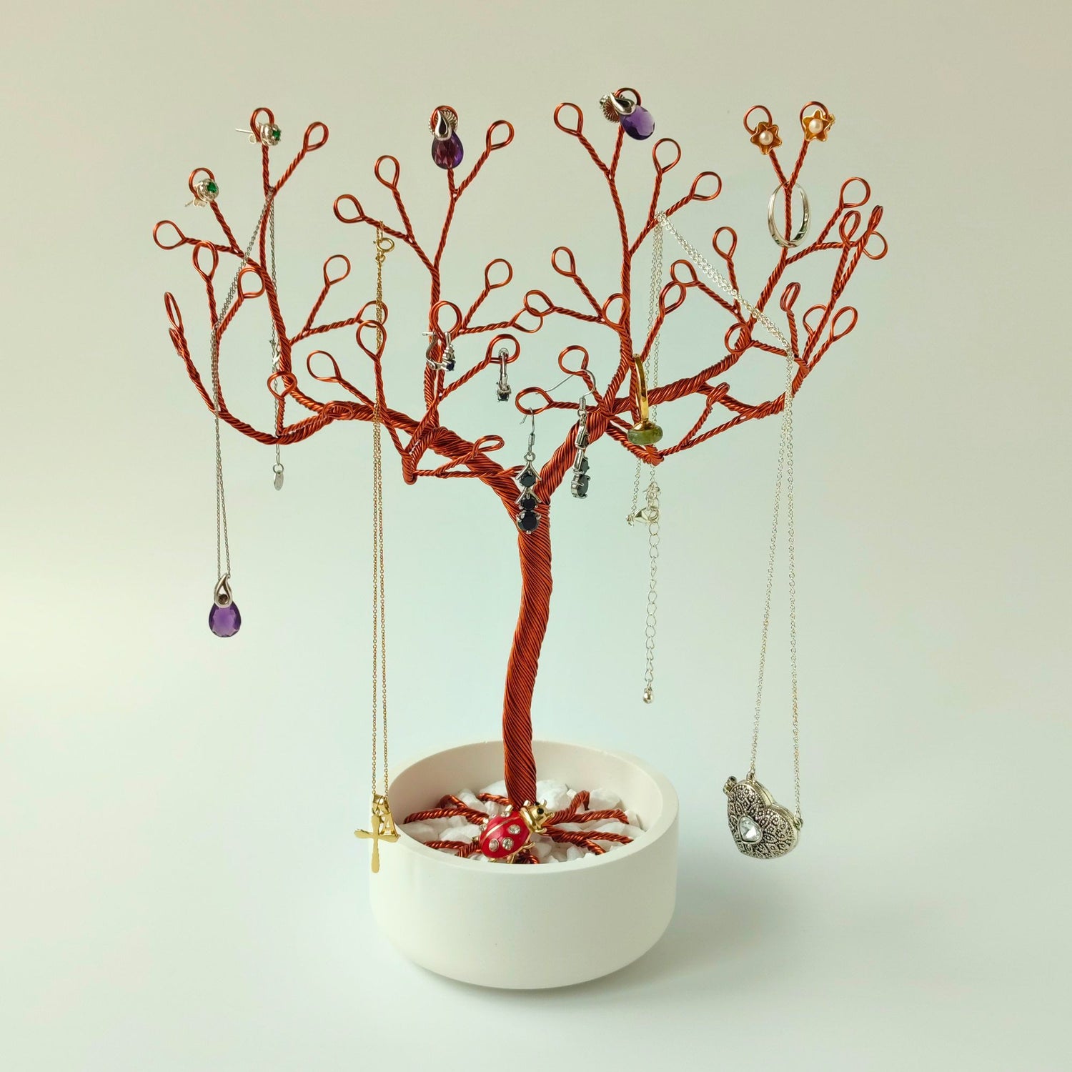 Jewelry tree made of copper wire in bowl with white stones