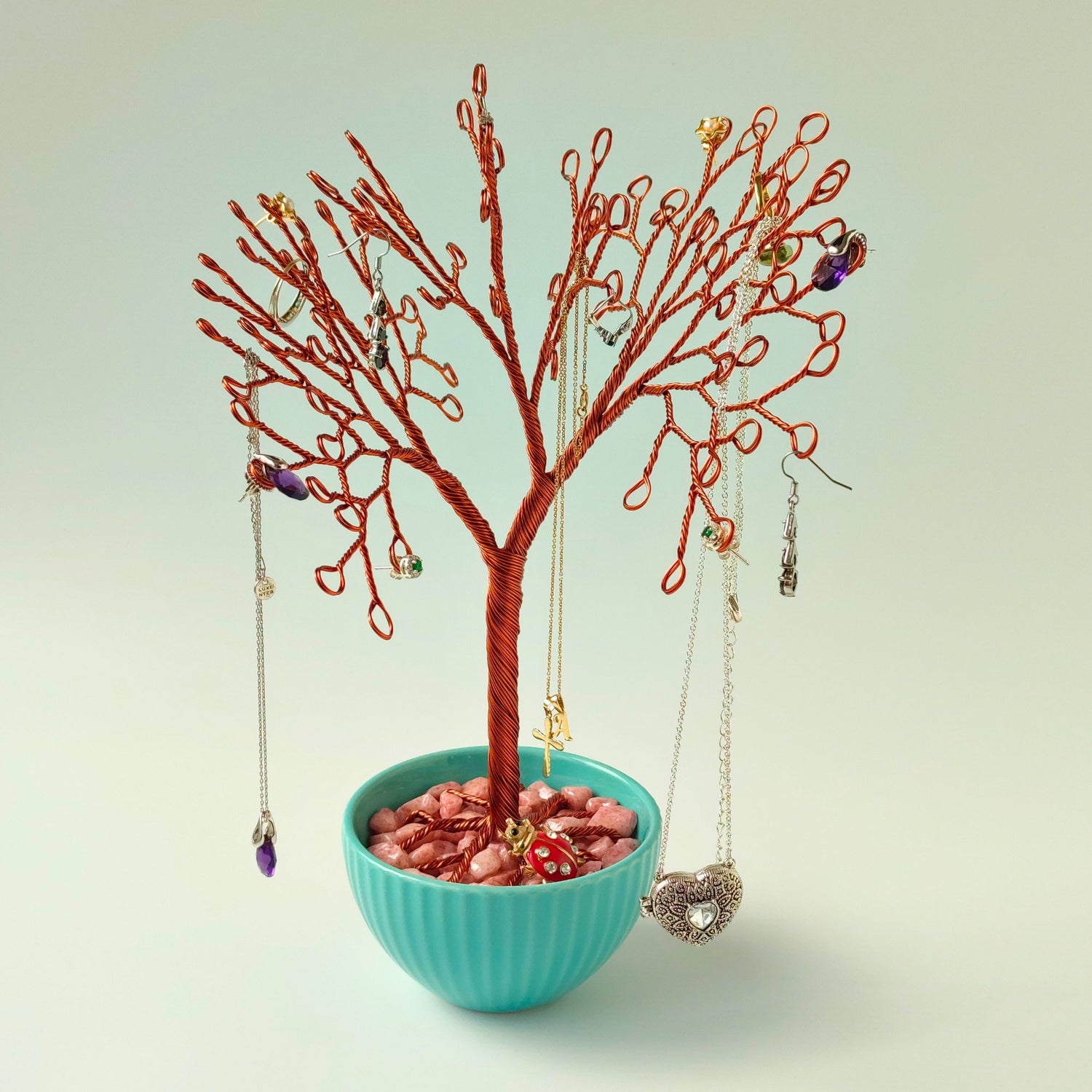 Copper jewelry tree with rings and earrings in turquoise bowl with pink stones