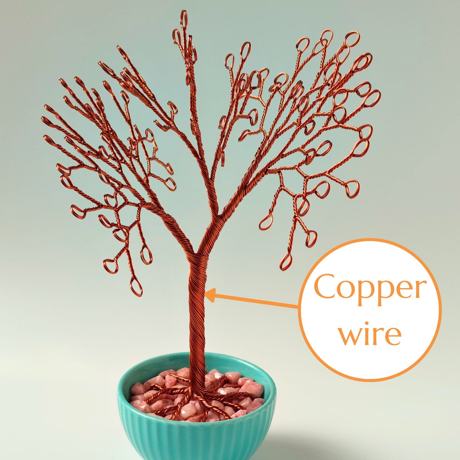 Close-up of copper wire jewelry stand trunk with material annotation and pink decorative stones