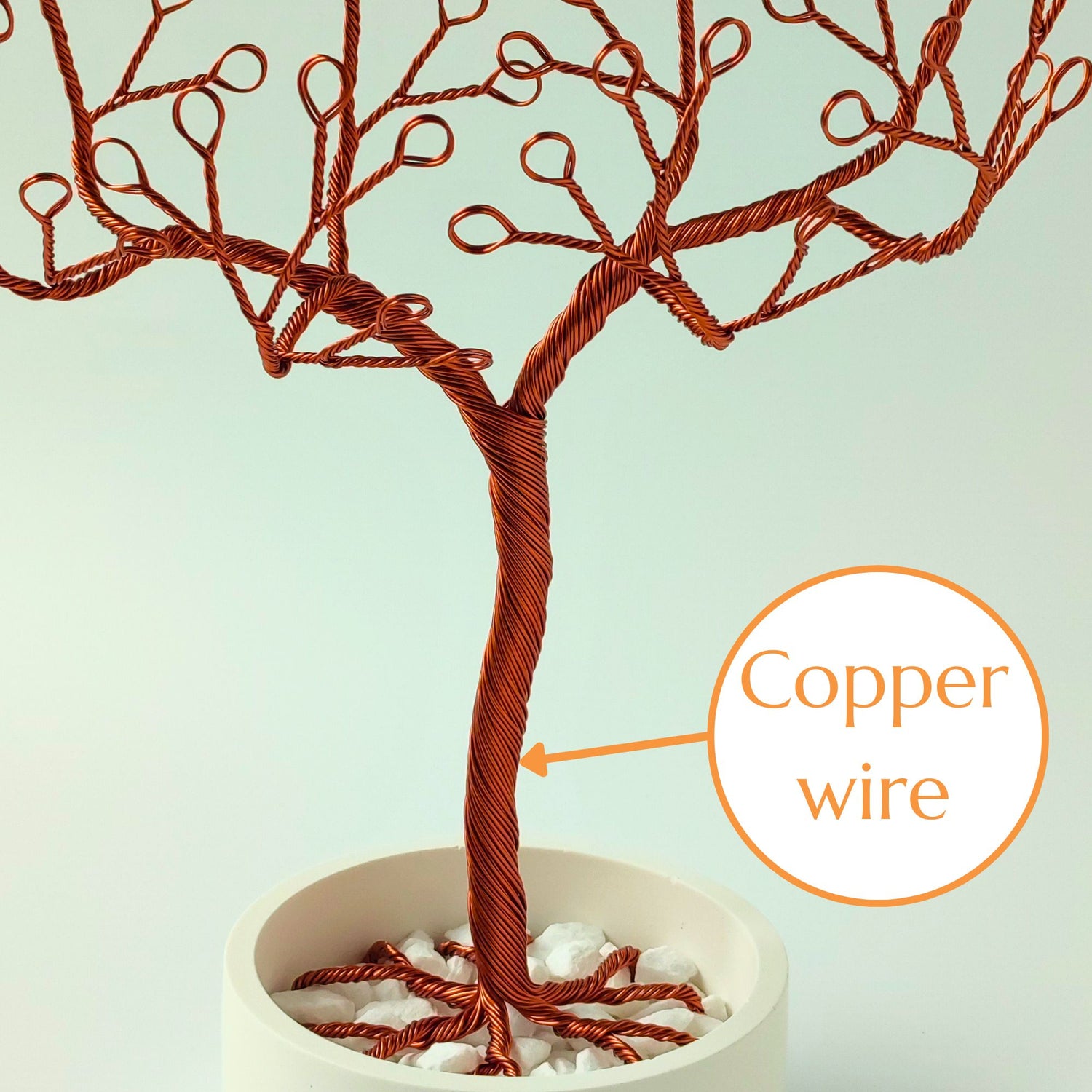 Close-up of copper wire jewelry stand trunk with material annotation and decorative stones