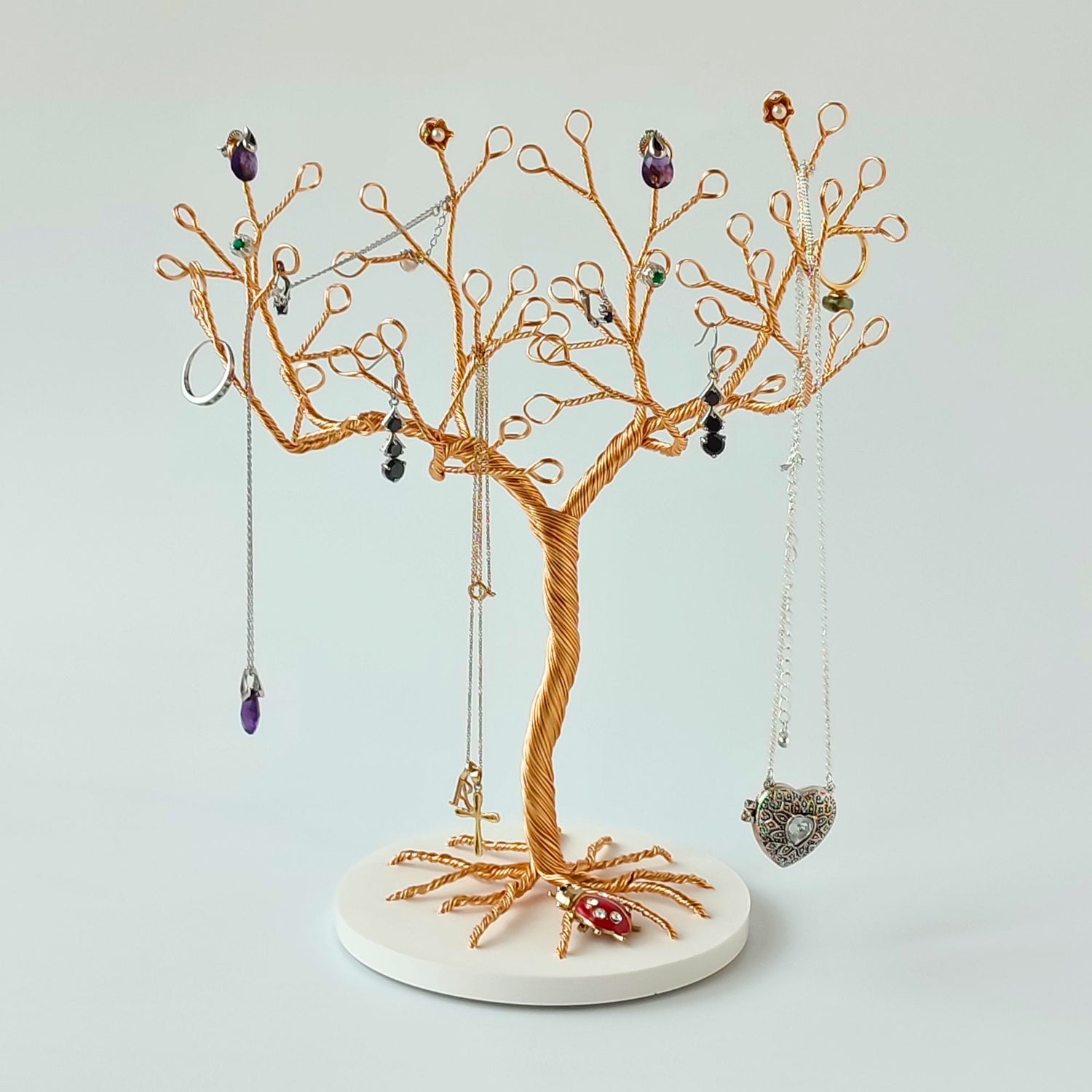 Gold jewelry tree stand with ceramic tray holding accessories