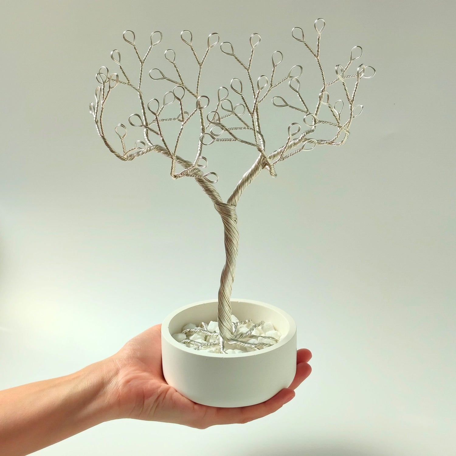 Silver jewelry holder with decorative stones shown in hand to show size and proportion