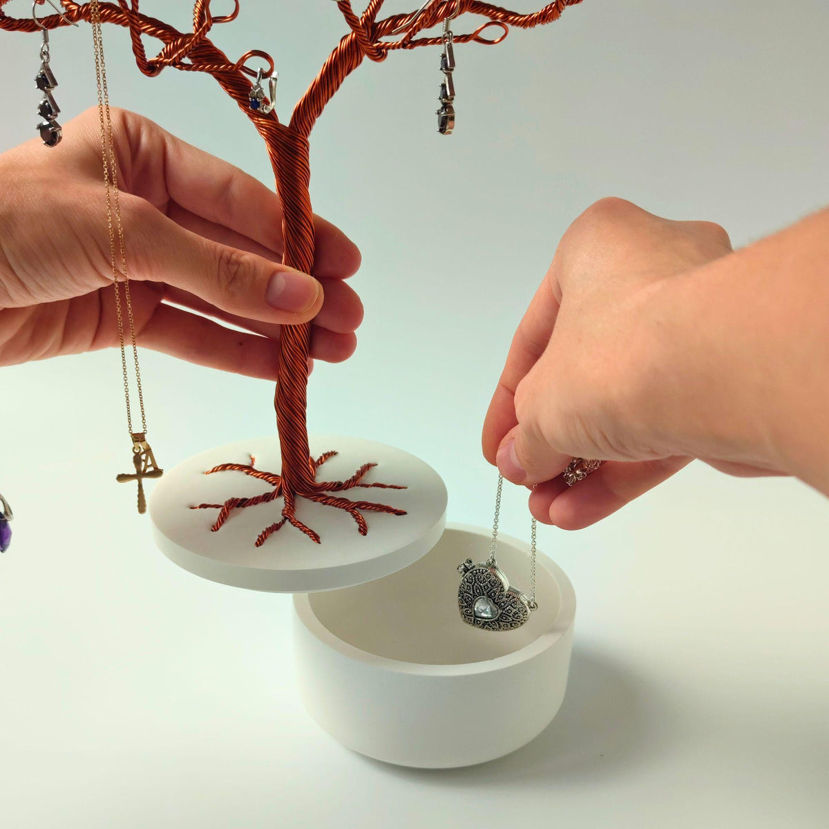 Hand lifting the tree and lid to store a pendant in the bowl