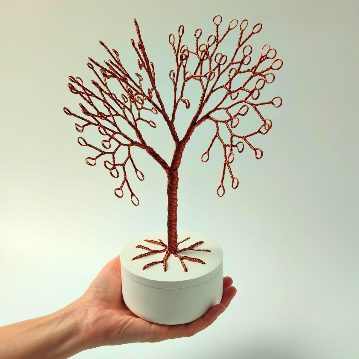 Copper jewelry tree held in a hand to show its size