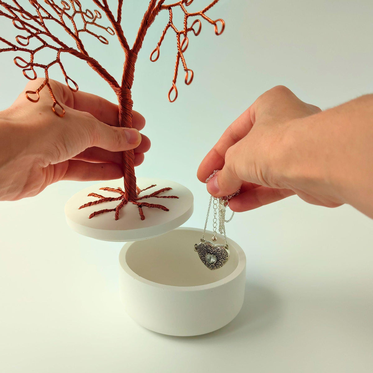 Hands lifting the bowl lid to store a necklace inside