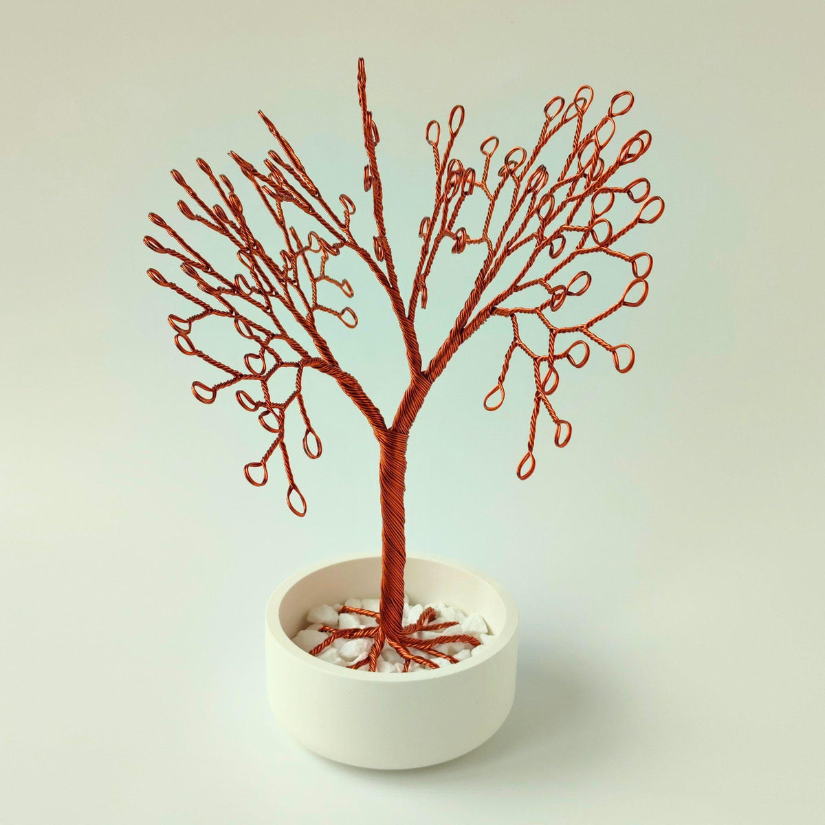 Copper wire tree in a round white bowl with white stones