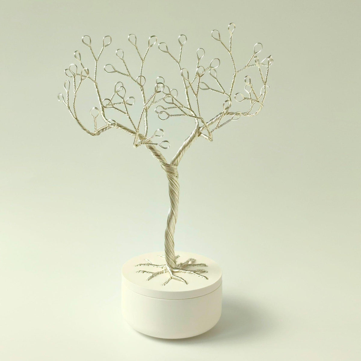 Silver wire tree with white pearl-like beads in a white lidded bowl