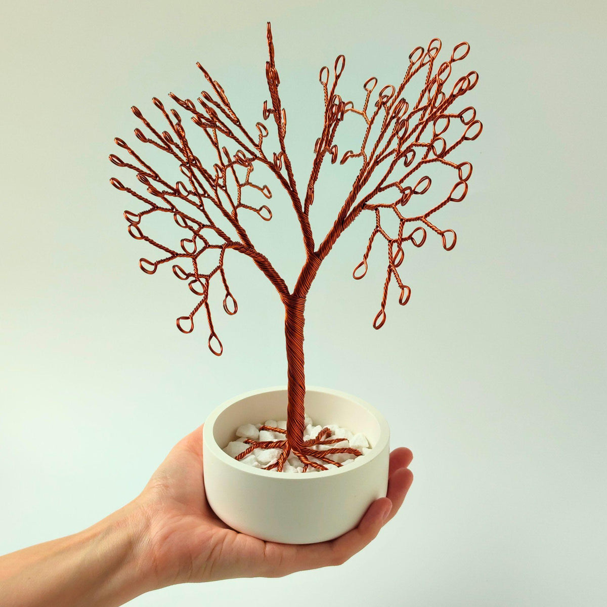 Copper jewelry tree held in a hand to show its size