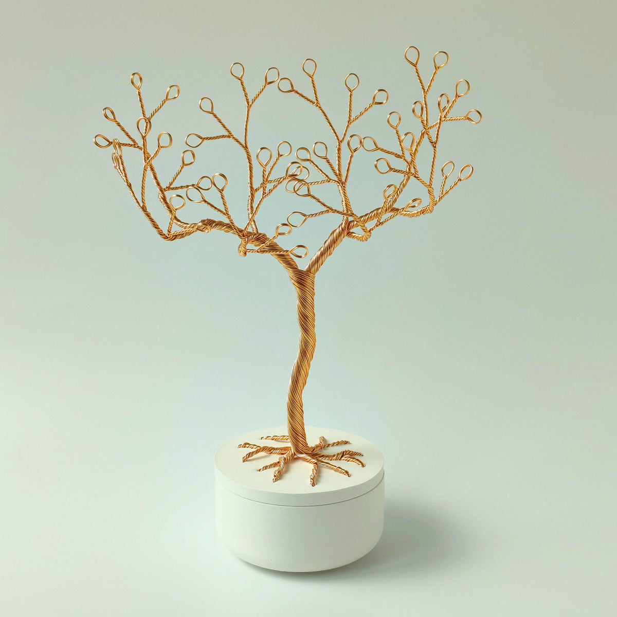 Gold wire tree on a white bowl with a root-pattern lid
