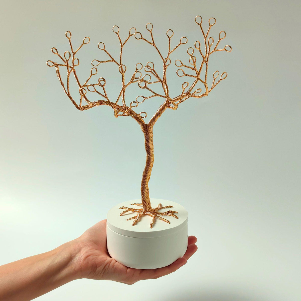 Gold jewelry tree held in a hand to show its size