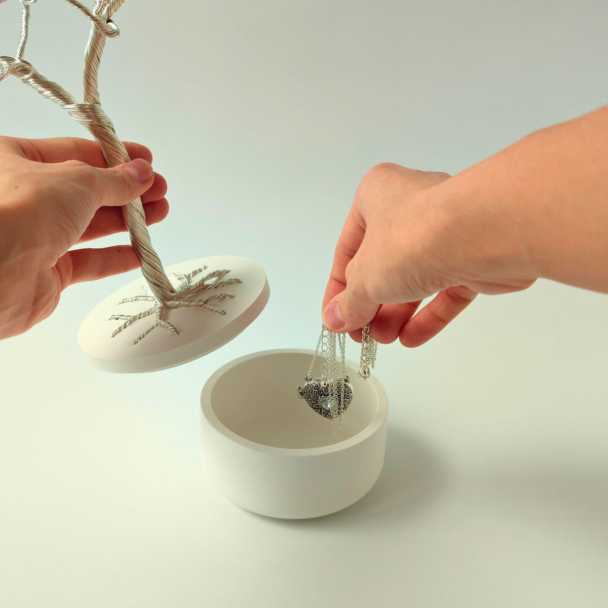 Hands lifting the white lid to store jewelry inside the bowl