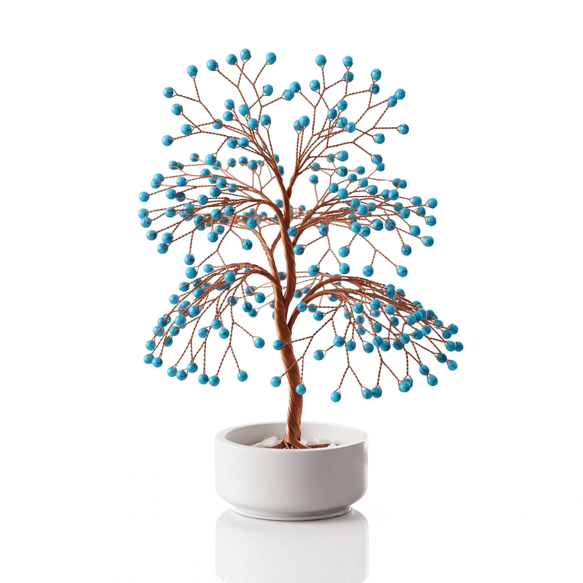 Copper wire tree with polished turquoise blue howlite spheres in a plain white ceramic bowl