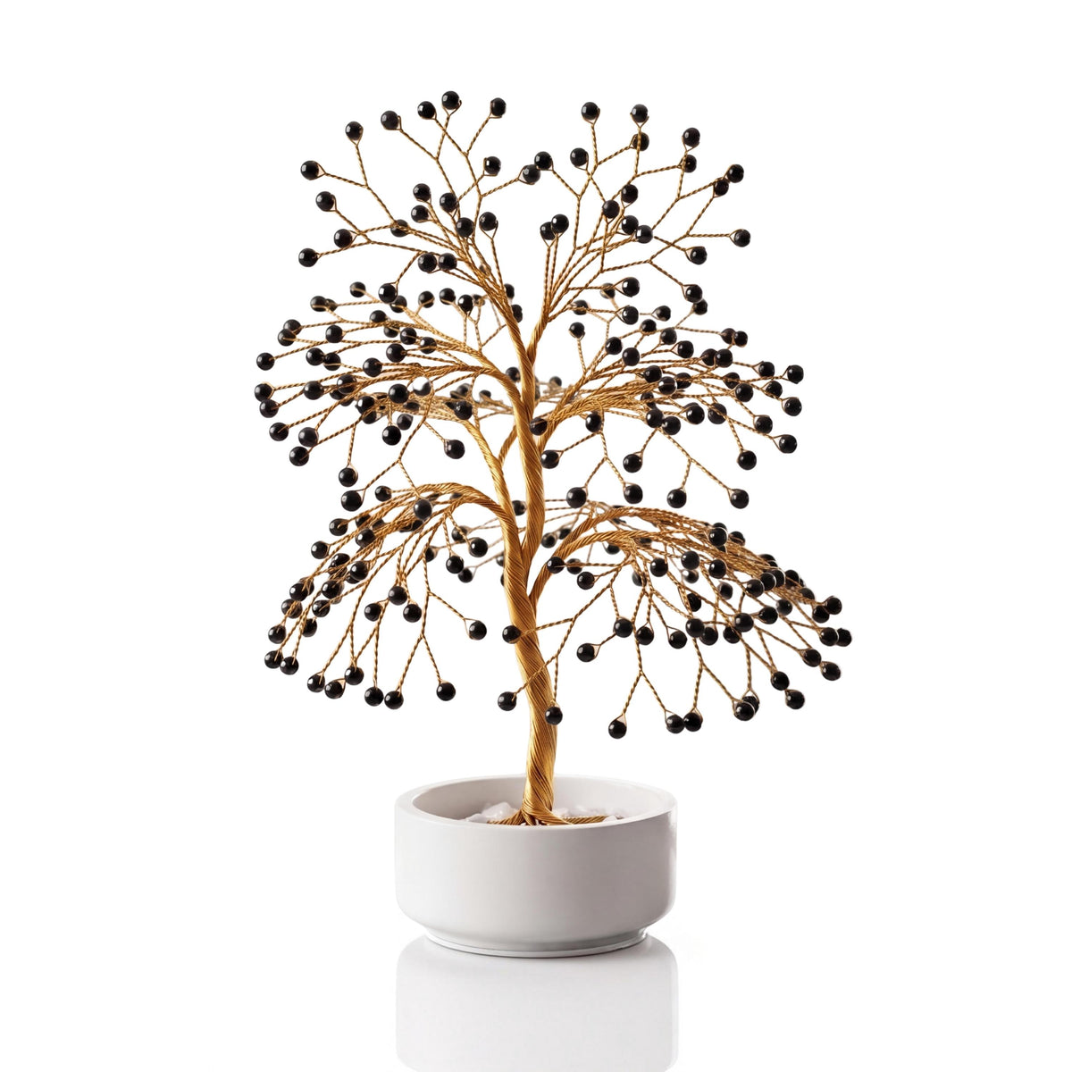 Gold-plated wire tree with polished glossy jet black obsidian spheres in a white ceramic bowl