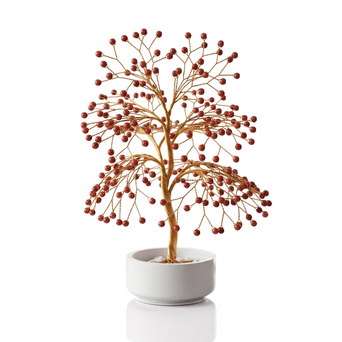 Gold-plated wire tree with polished rich brick red jasper spheres in a white ceramic bowl