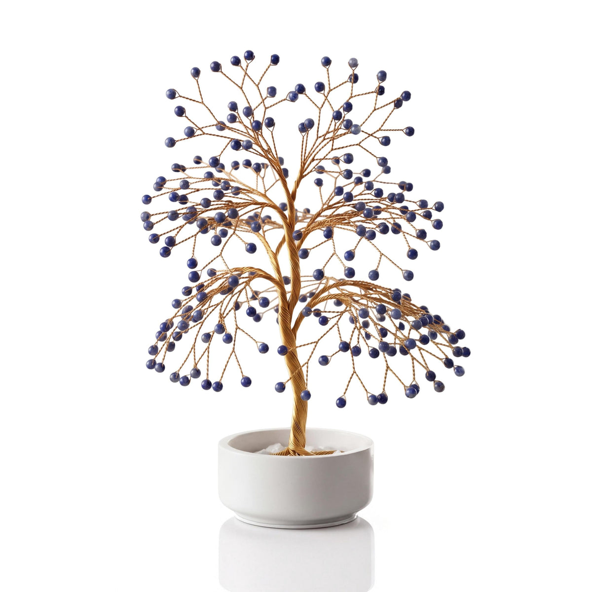 Gold-plated wire tree with polished royal blue lapis lazuli spheres in a white ceramic bowl