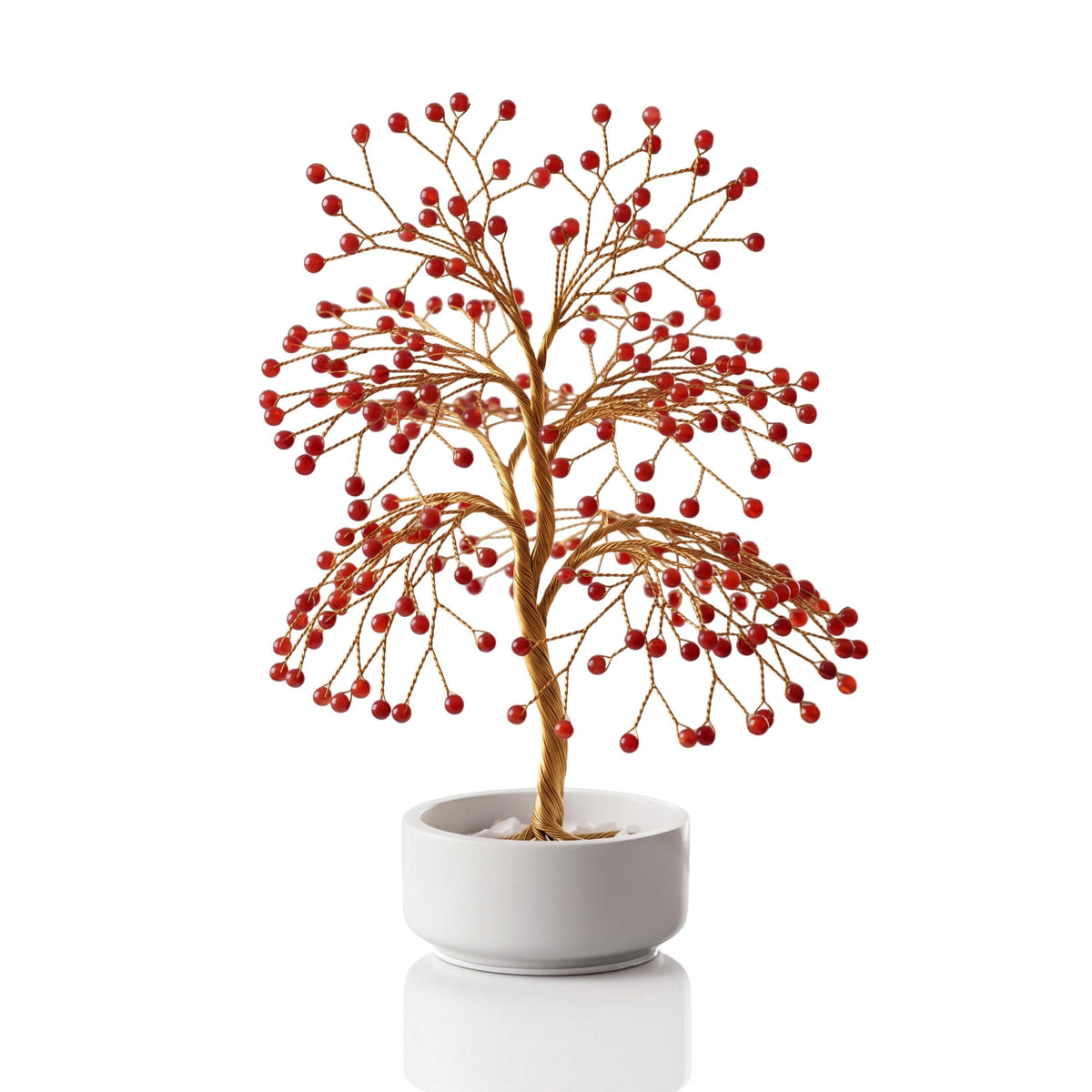 Gold-plated wire tree with polished deep cherry red carnelian spheres in a white ceramic bowl