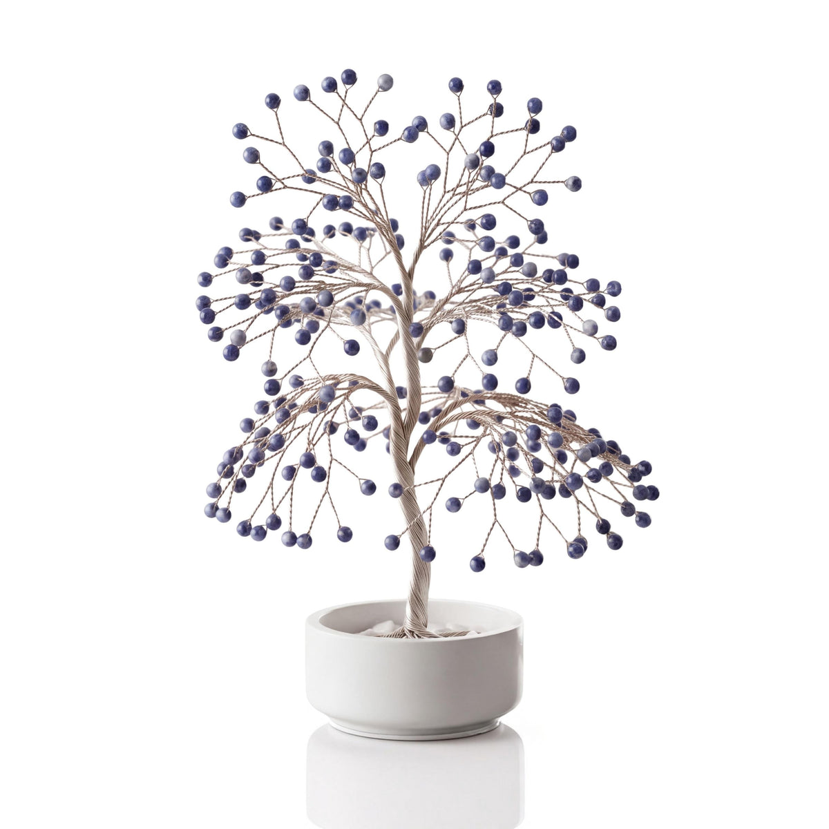 Silver-plated wire tree with polished deep royal blue sodalite spheres in a white ceramic bowl