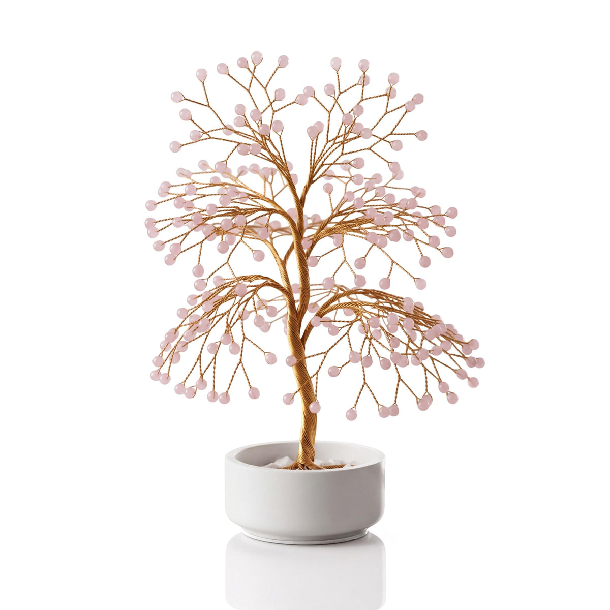 Gold-plated wire tree with polished pale pink rose quartz spheres in a white ceramic bowl