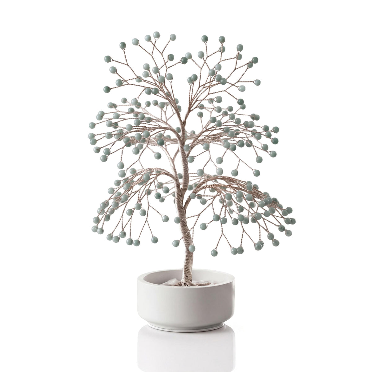 Silver-plated wire tree with polished pale green Burmese jadeite beads in a white ceramic bowl