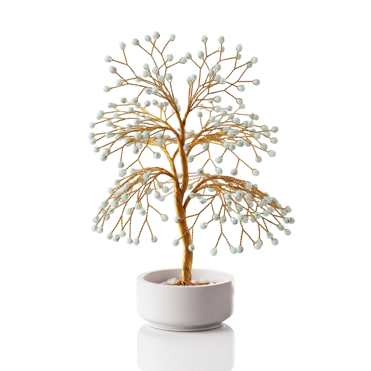 Gold-plated wire tree with polished mint green hemimorphite beads in a white ceramic bowl