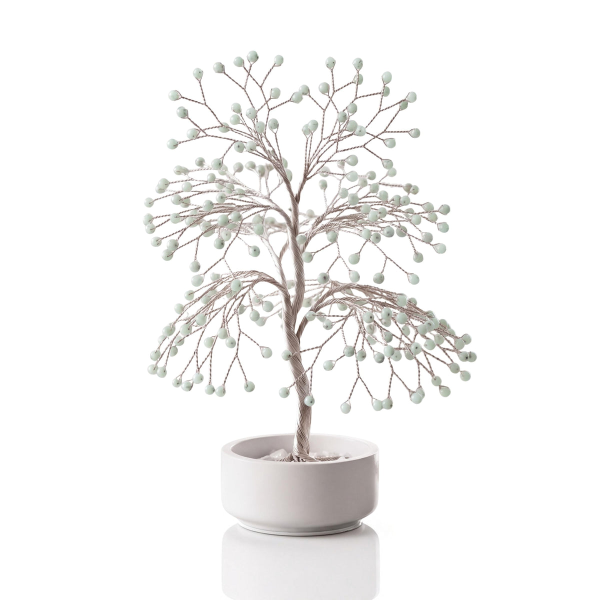 Silver-plated wire tree with polished mint green hemimorphite beads in a white ceramic bowl