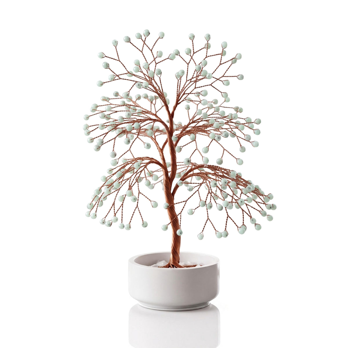Copper wire tree with polished mint green hemimorphite beads in a plain white ceramic bowl