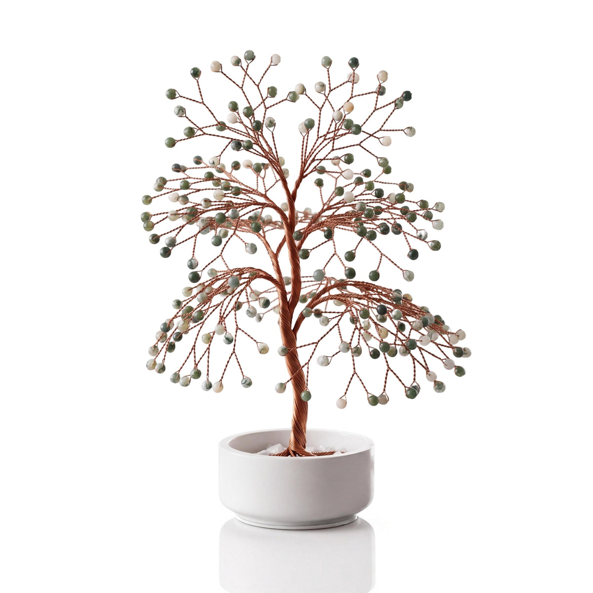 Copper wire tree with polished white and green tree agate beads in a plain white ceramic bowl
