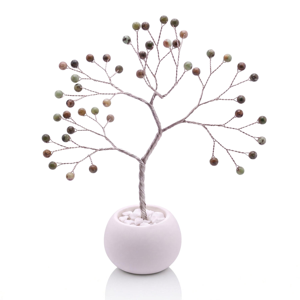 Silver-plated wire tree with polished pistachio green opal beads in a white bowl with white pebbles