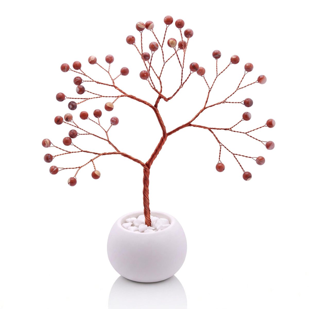 Copper wire tree with polished canyon red jasper beads with white veins in a plain white bowl filled with white pebbles