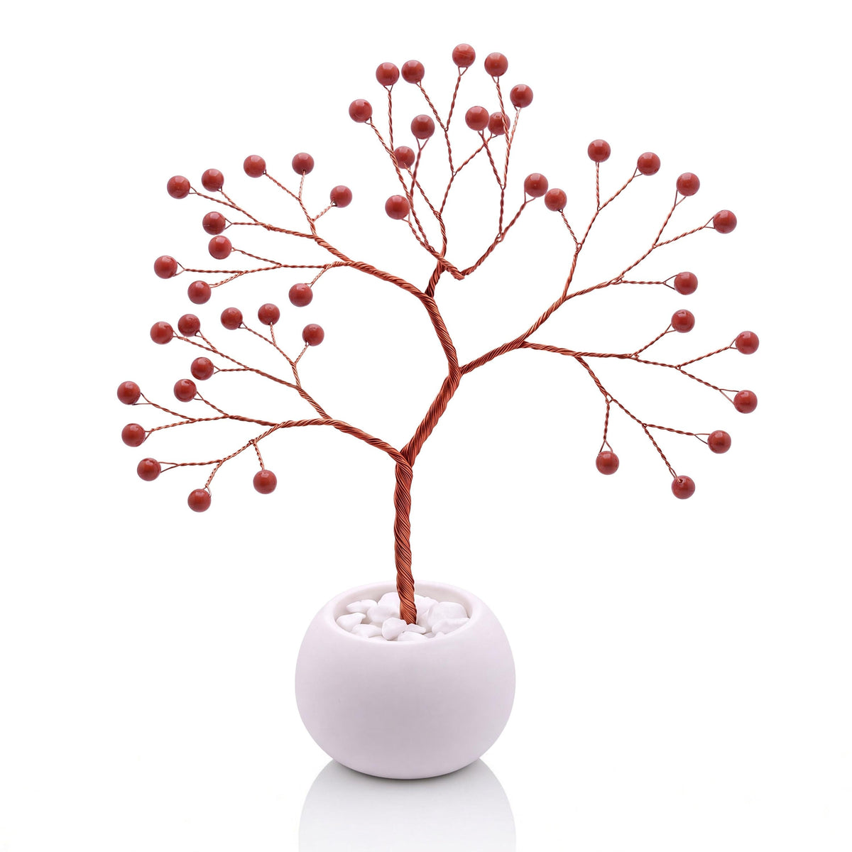 Copper wire tree with polished brick red jasper beads in a plain white bowl filled with white pebbles