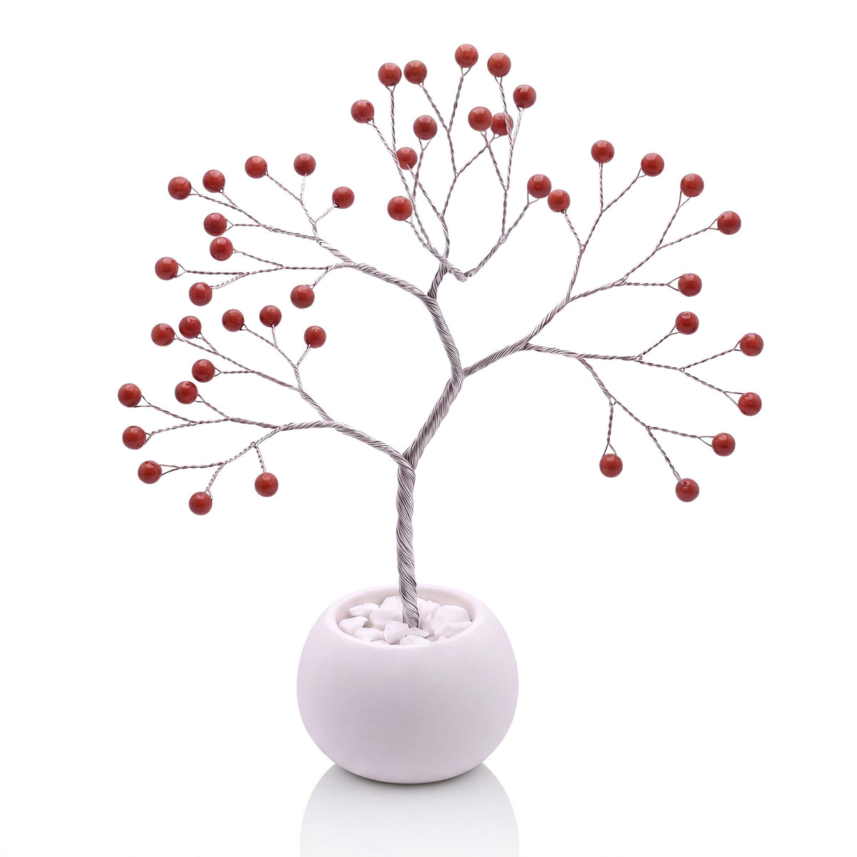 Silver-plated wire tree with polished brick red jasper beads in a white bowl with white pebbles