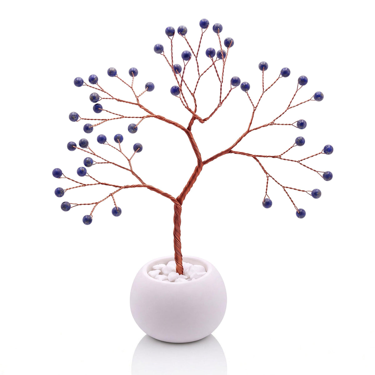 Copper wire tree with polished deep blue lapis lazuli beads in a plain white bowl filled with white pebbles