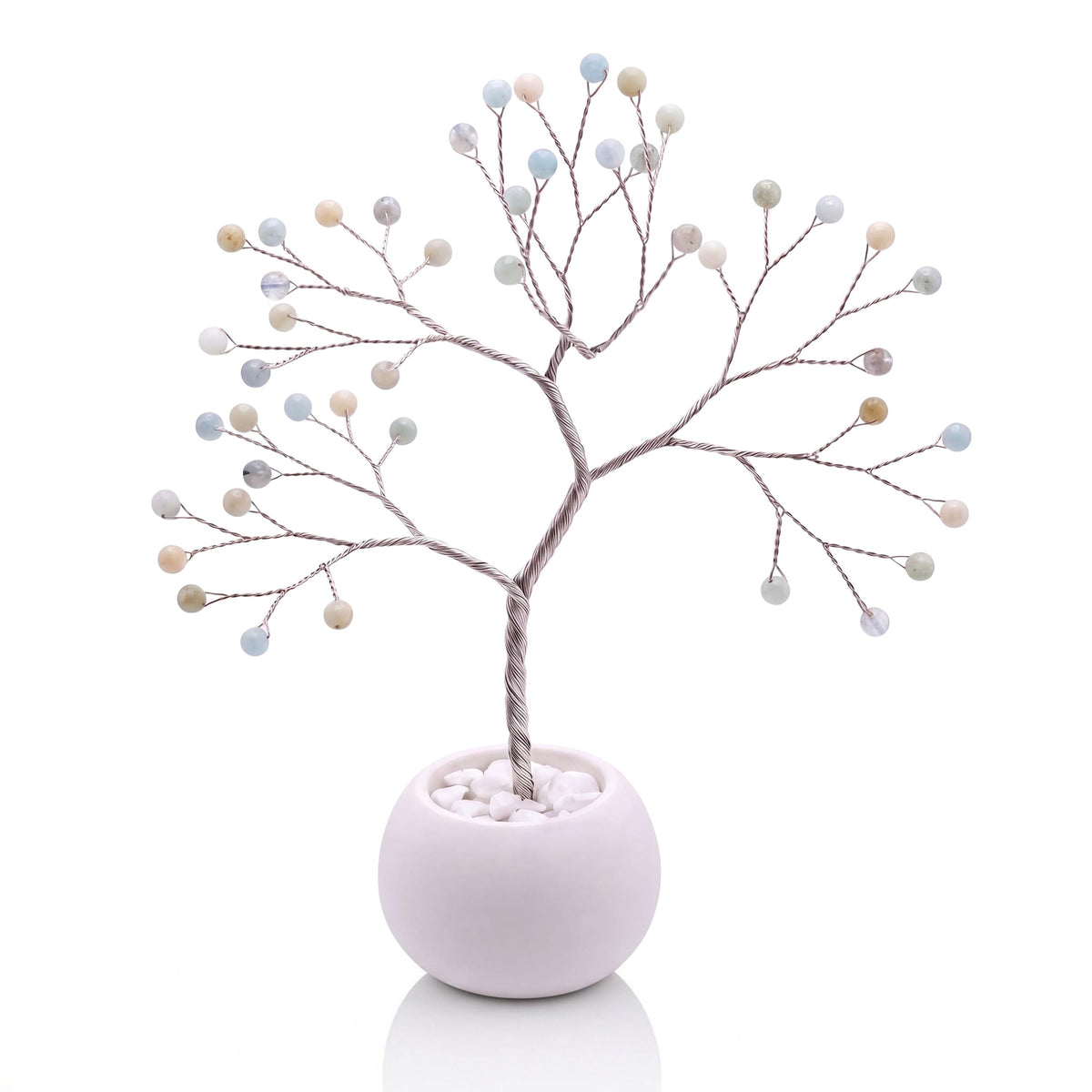 Silver-plated wire tree with polished milky sea blue aquamarine beads in a white bowl with white pebbles