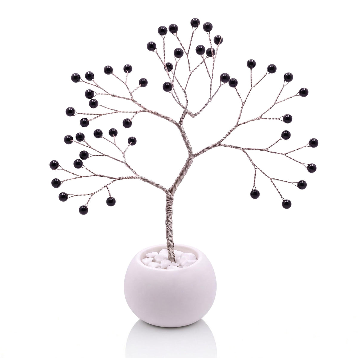 Silver-plated wire tree with polished glossy black obsidian beads in a white bowl with white pebbles