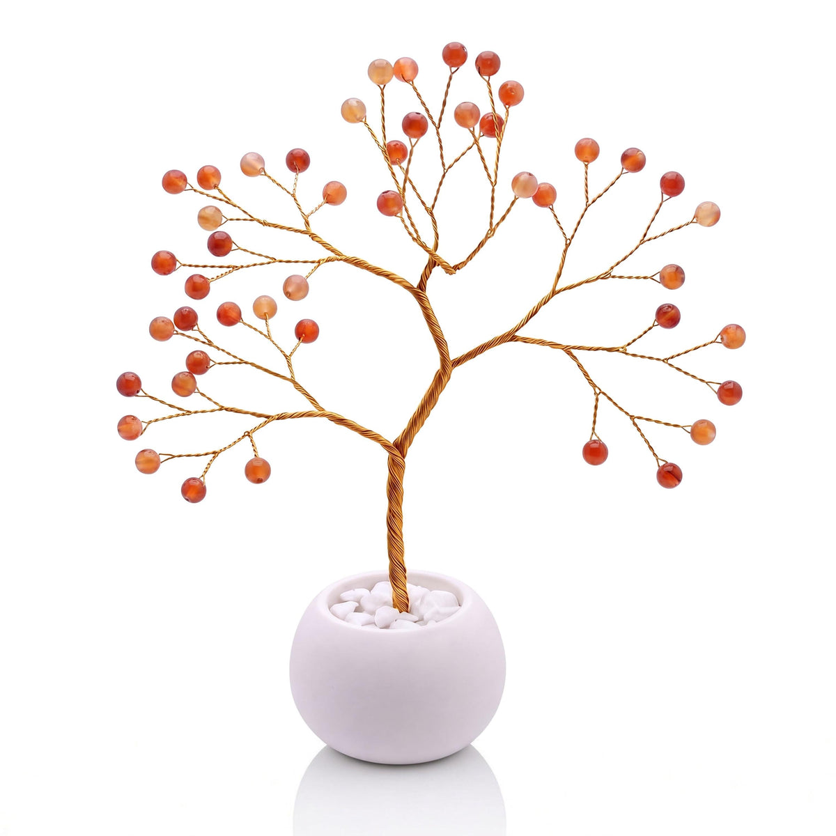 Gold-plated wire tree with polished marmalade orange carnelian beads in a white bowl with white pebbles