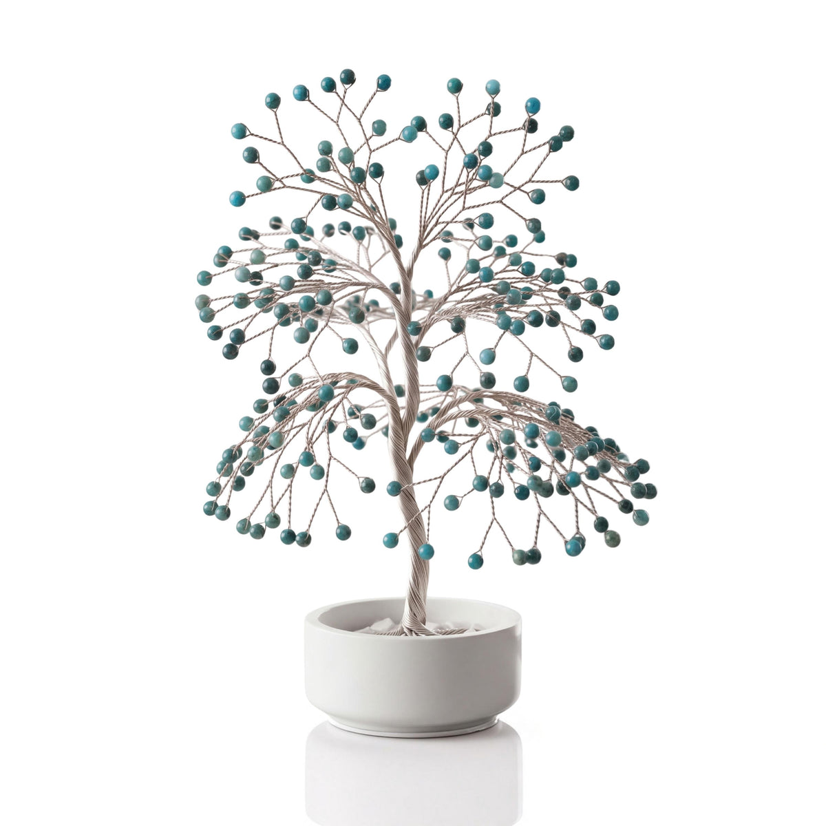 Silver-plated wire tree with polished teal blue apatite spheres in a white ceramic bowl