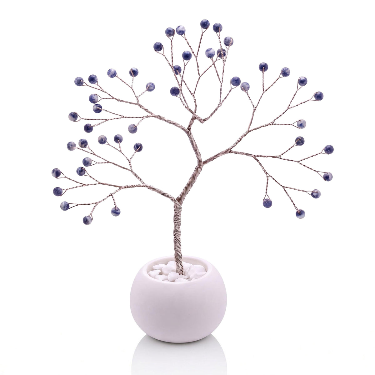 Silver-plated wire tree with polished denim blue sodalite beads with white veining in a white bowl with white pebbles