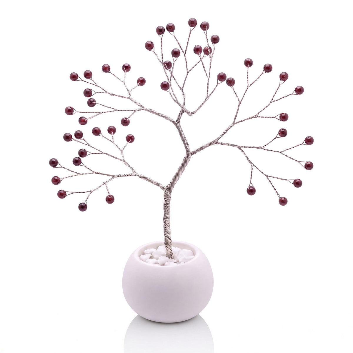 Silver-plated wire tree with polished black cherry red garnet beads in a white bowl with white pebbles