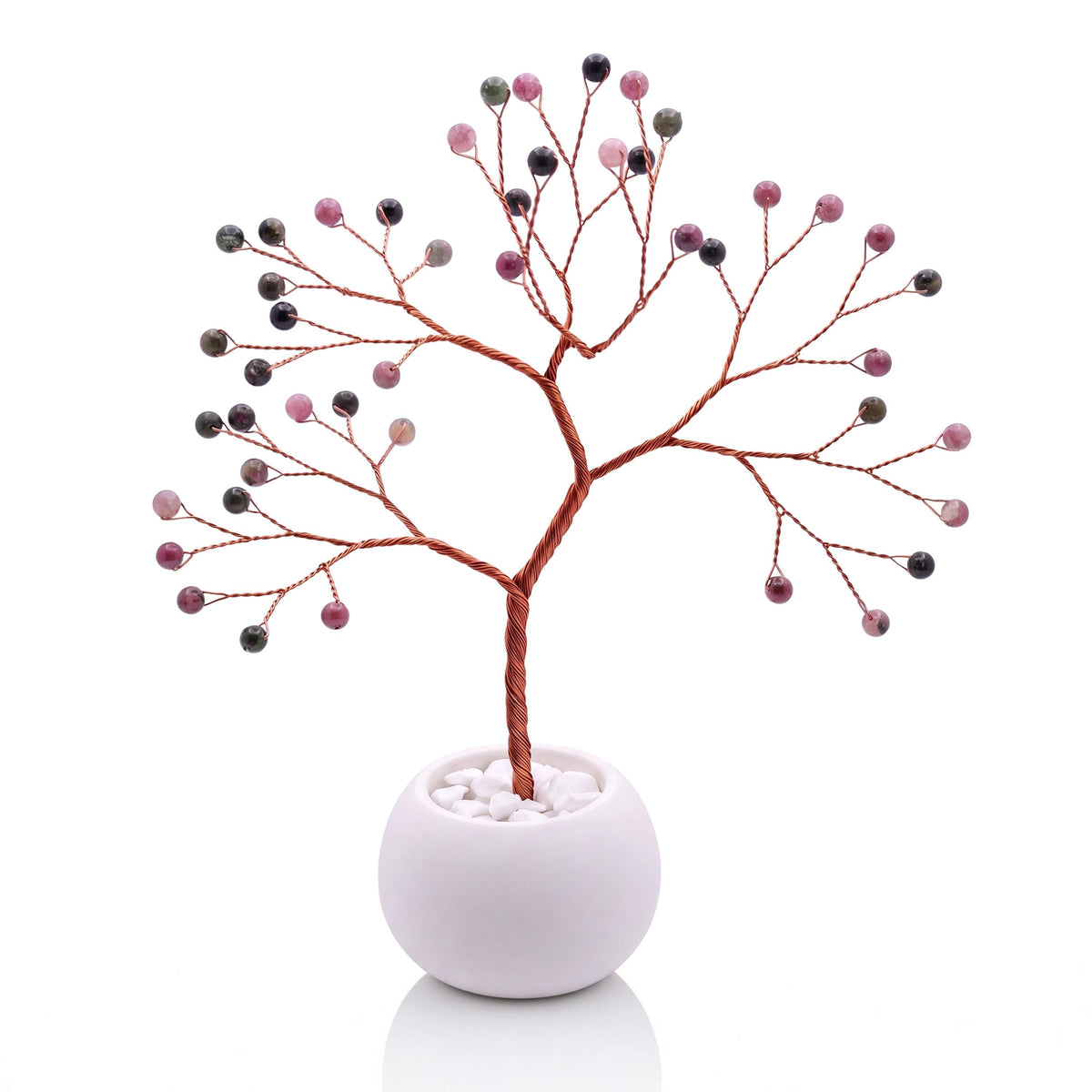 Copper wire tree with polished rhubarb pink and sage green tourmaline beads in a plain white bowl filled with white pebbles