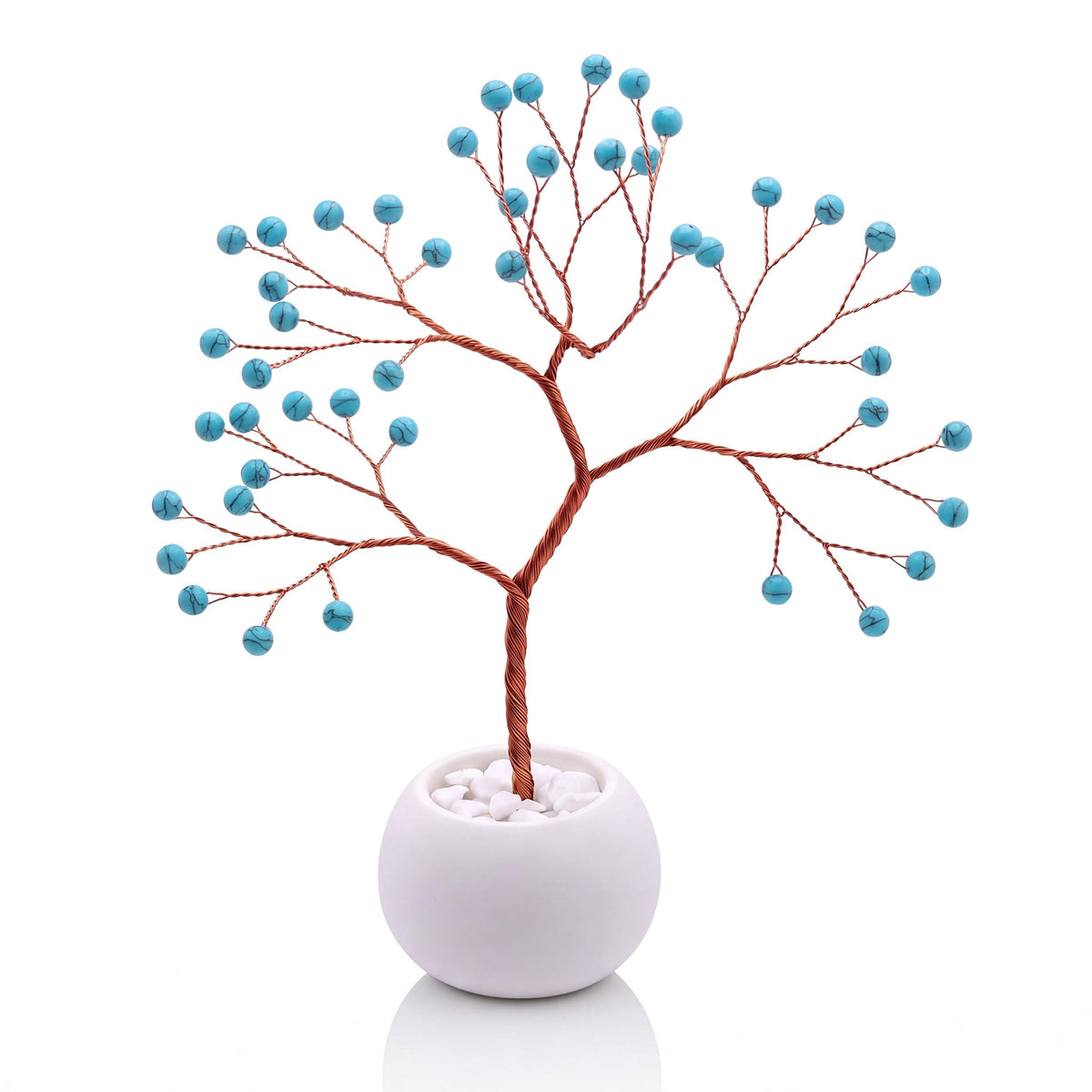 Copper wire tree with polished robin's egg blue howlite beads in a plain white bowl filled with white pebbles