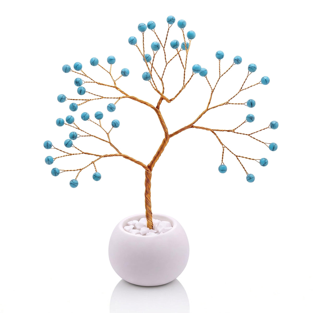 Gold-plated wire tree with polished robin's egg blue howlite beads in a white bowl with white pebbles