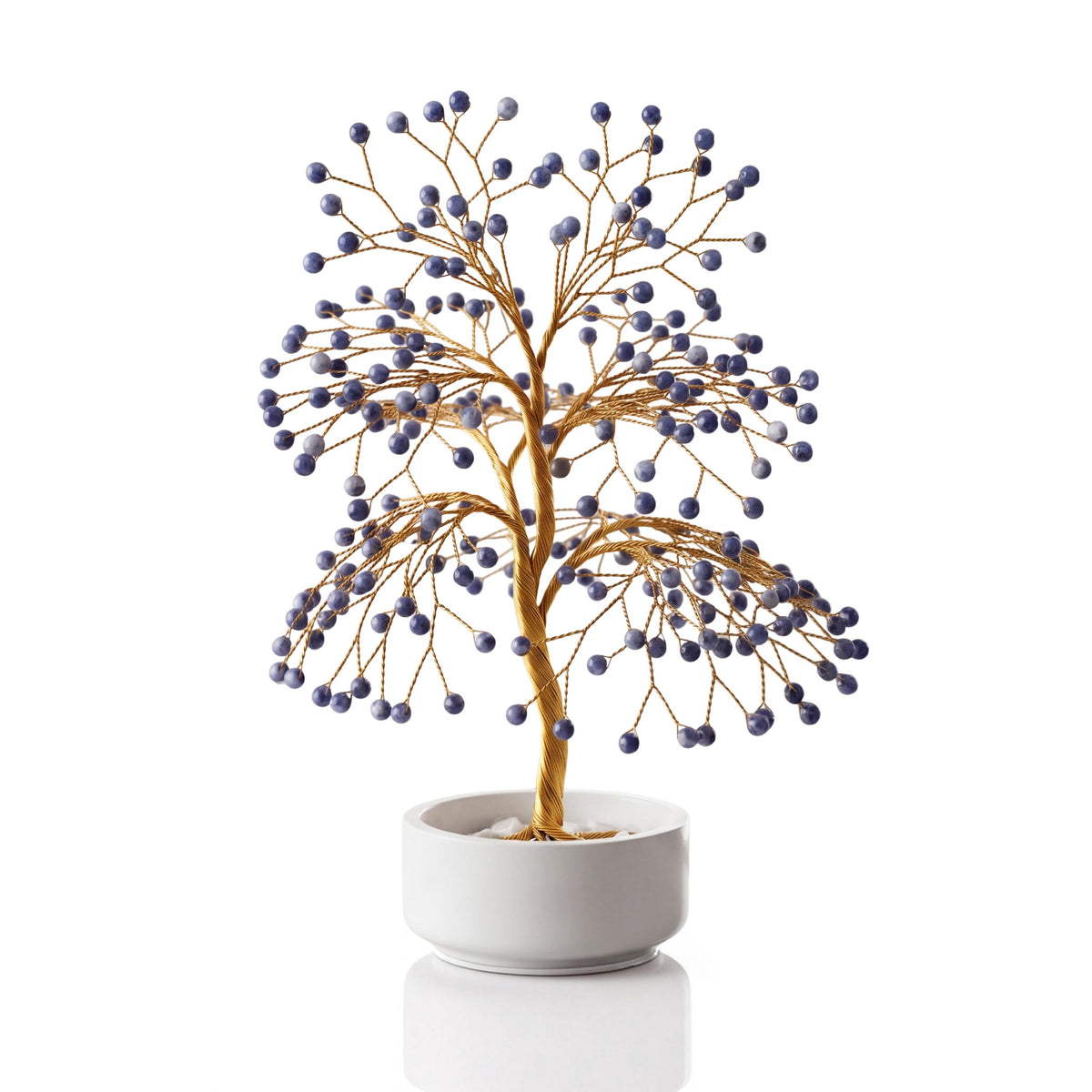 Gold-plated wire tree with polished deep royal blue sodalite spheres in a white ceramic bowl